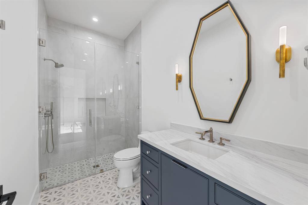 Located on the first floor for ultimate accessibility, this secondary suite blends comfort with sophisticated design. The attached bathroom features curated materials—designer tile, modern fixtures, and a frameless glass shower—offering a spa-like experience in a private, peaceful setting.