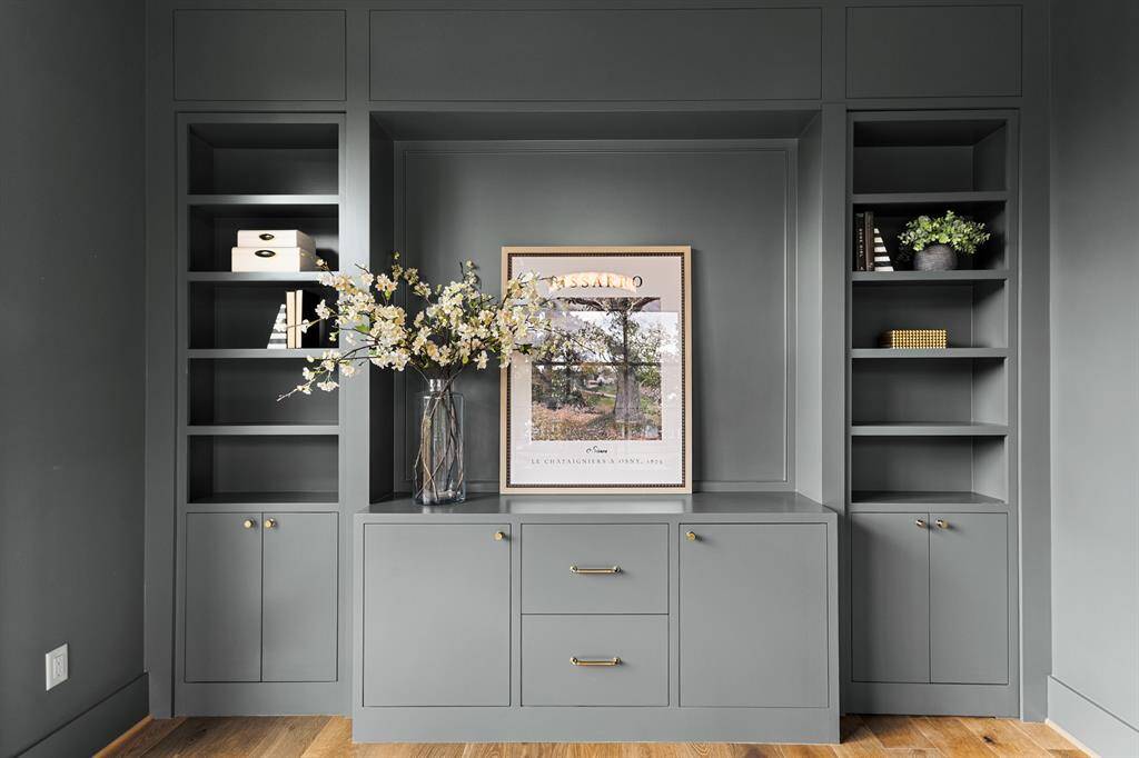 This moody office features oversized windows that allow soft, natural light to pour in, creating a balanced, inviting atmosphere. Custom bookshelves line the walls, offering both style and storage, while a "hidden" closet seamlessly blends into the design, adding an element of surprise and functionality.