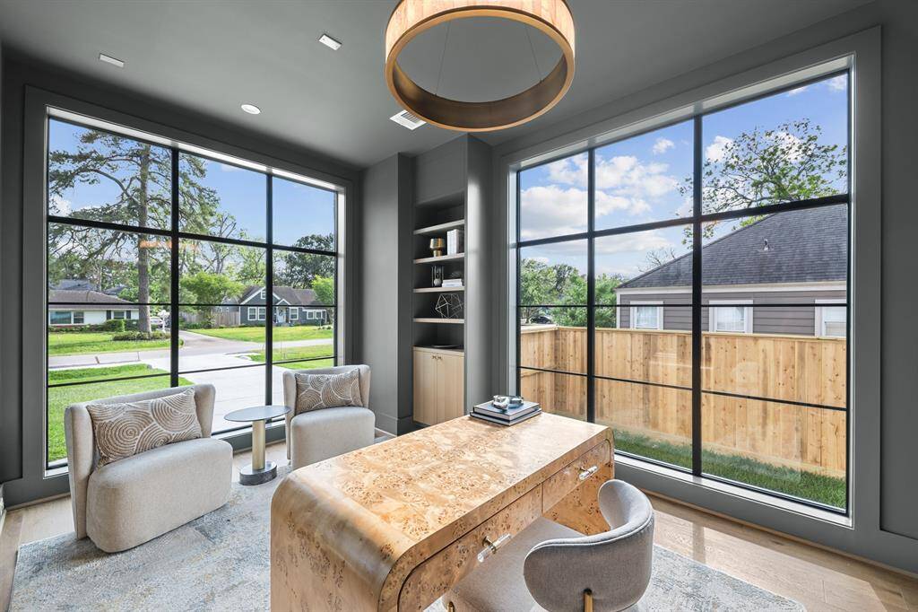 This moody office features oversized windows that allow soft, natural light to pour in, creating a balanced, inviting atmosphere. Custom bookshelves line the walls, offering both style and storage, while a "hidden" closet seamlessly blends into the design, adding an element of surprise and functionality.