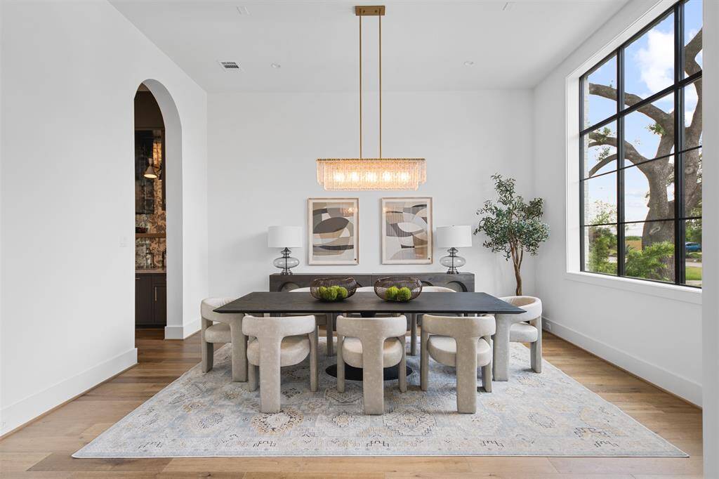 This elegant formal dining room offers a versatile space with abundant natural light, high ceilings, and a statement chandelier, making it perfect for hosting or transforming into a stylish home office or lounge.