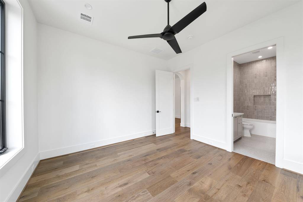 One of five thoughtfully designed secondary bedrooms, this upstairs suite features generous proportions, wide-plank white oak flooring, and abundant natural light. The ensuite bath continues the elevated aesthetic with designer tile, modern fixtures, and a seamless walk-in shower.
