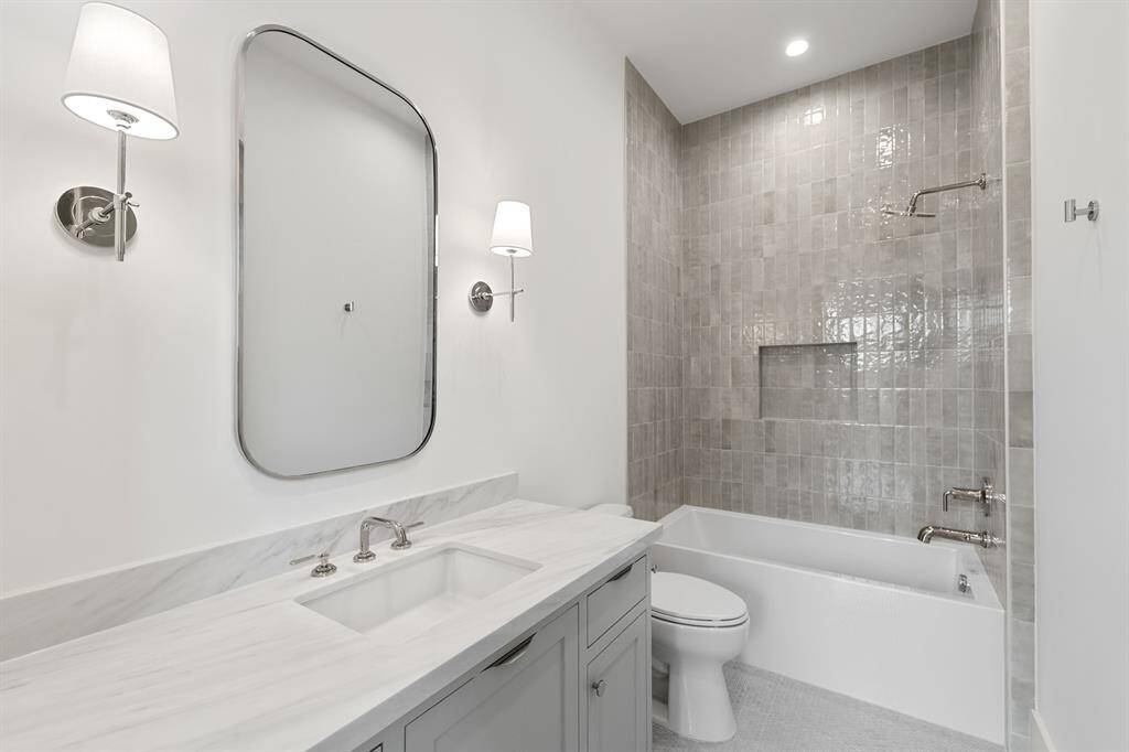 This secondary bath combines practicality with elegance, featuring a beautifully tiled tub-shower combo. The clean lines of the modern fixtures and soft neutral tones create a serene retreat, while designer tile adds texture and sophistication to the space. It’s a perfect blend of comfort and style for everyday use.