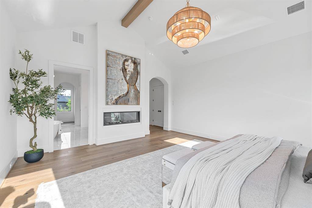 This serene primary suite features beautiful white oak hardwood floors that add warmth and elegance to the space. An abundance of natural light pours in through the windows, filling the room with a bright, airy ambiance that enhances the peaceful and inviting atmosphere.