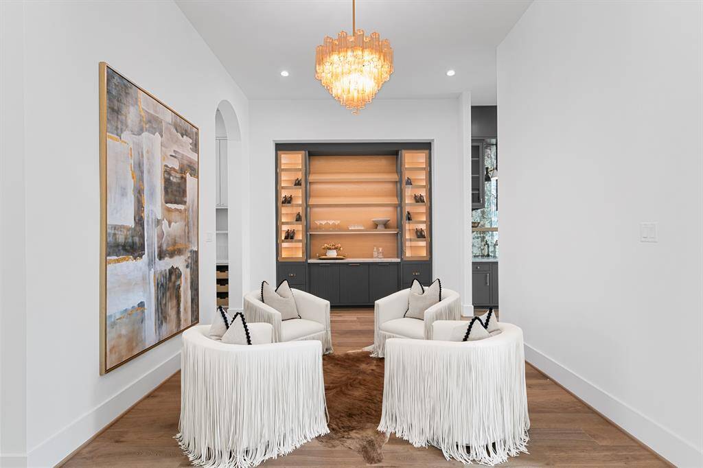 This sophisticated lounge features custom built-in cabinetry with illuminated shelving, creating a warm and inviting space perfect for displaying décor or entertaining in style.