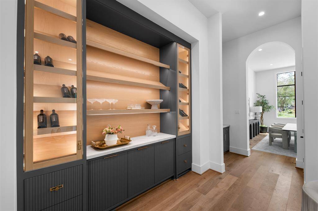 This sophisticated lounge features custom built-in cabinetry with illuminated shelving, creating a warm and inviting space perfect for displaying décor or entertaining in style.