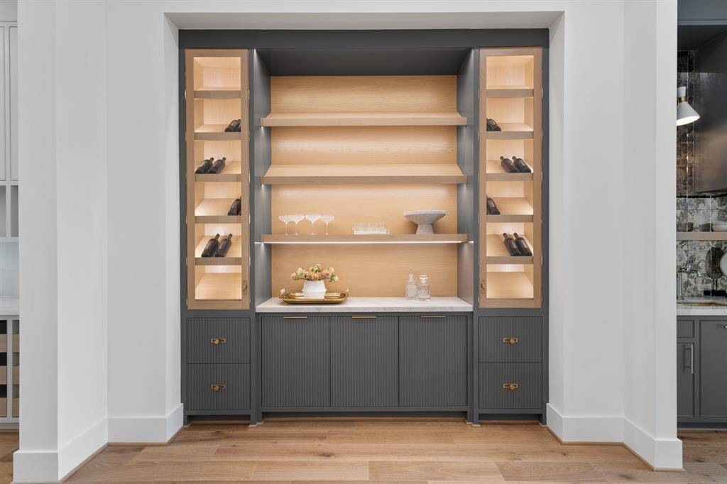 This sophisticated lounge features custom built-in cabinetry with illuminated shelving, creating a warm and inviting space perfect for displaying décor or entertaining in style.