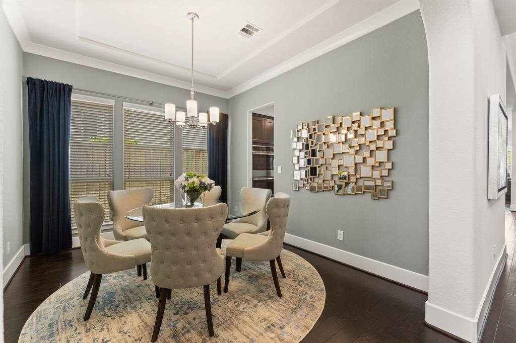 The elegant formal dining room is framed by large windows, a tray ceiling, and designer lighting—perfect for hosting intimate dinners or holiday celebrations.