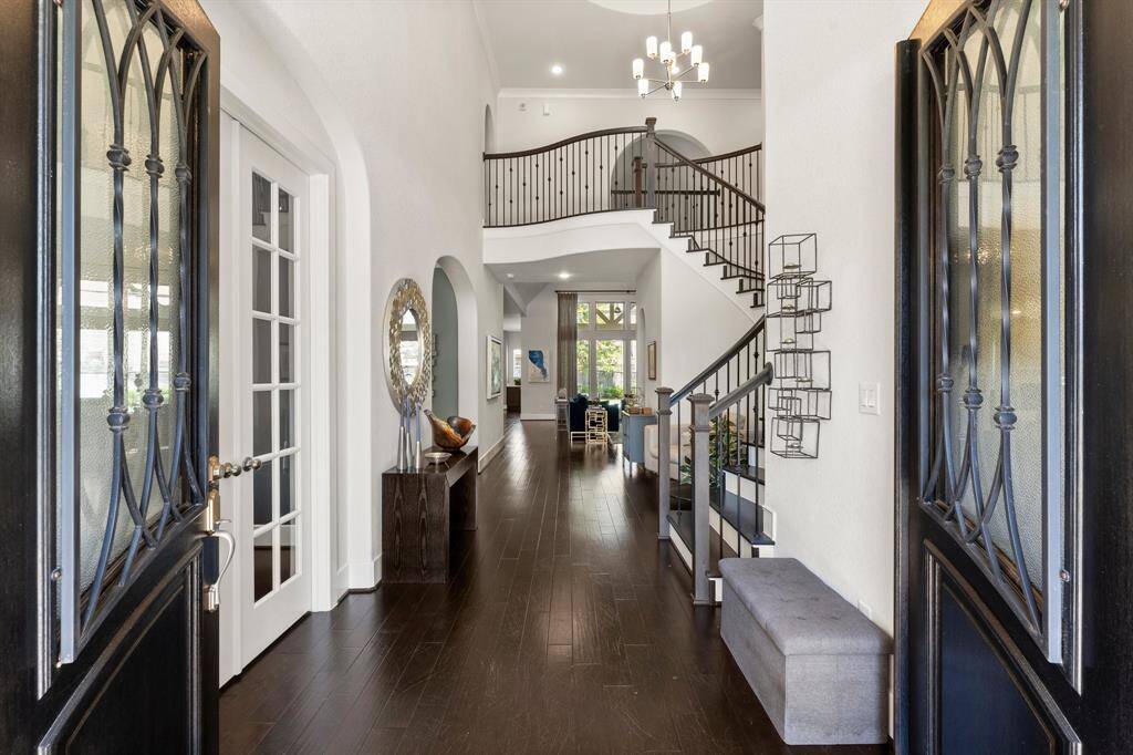 Grand two-story foyer with elegant hardwood flooring, arched openings, and iron-railed staircase sets the tone for this impeccably designed home.