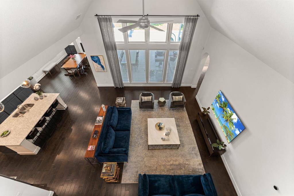 A dramatic view from the second-floor landing captures the soaring ceilings, elegant open layout, and wall of windows flooding the home with natural light.