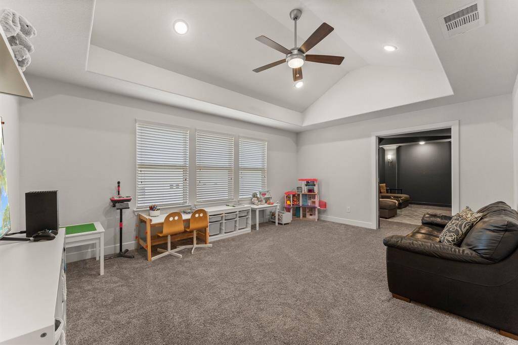 Expansive upstairs game room offers flexible space for play, hobbies, or lounging, with high ceilings and soft carpeting for comfort.