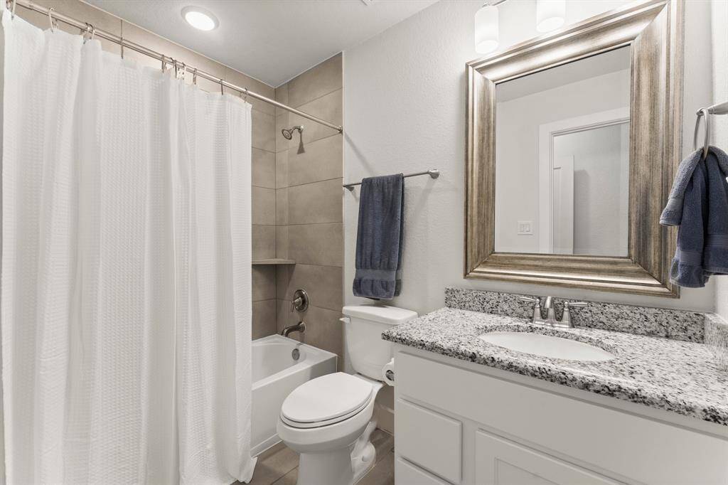 Beautifully appointed full bath with neutral tones, granite counters, and a tiled tub/shower combination.