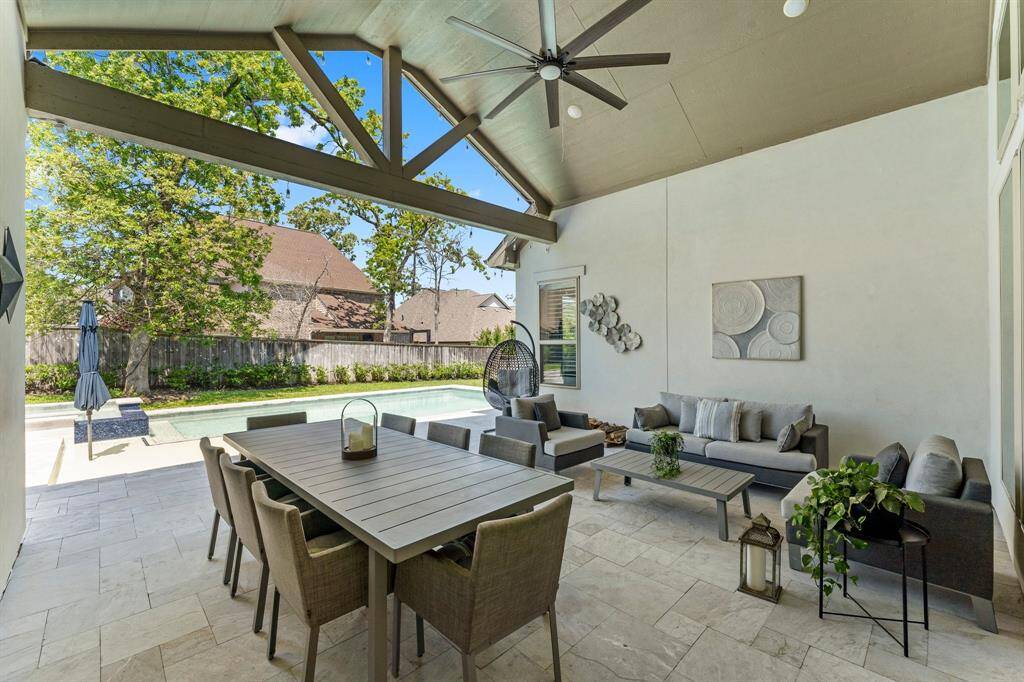 Experience elevated outdoor living beneath soaring vaulted ceilings with exposed beams and a statement-making oversized fan. This expansive covered patio offers sophisticated lounging and dining areas, perfect for hosting in comfort and style.