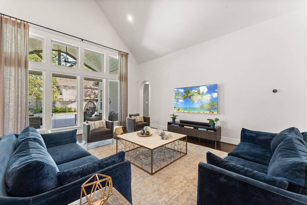 Soaring ceilings and a wall of windows fill the family room with natural light, offering views of the covered patio and pool beyond.