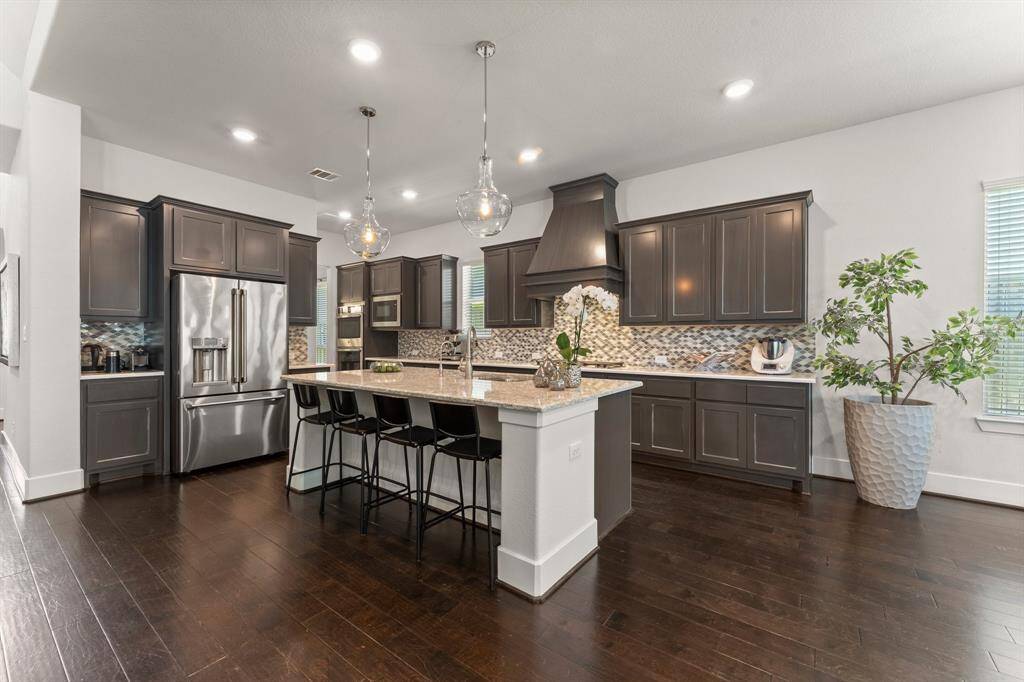 This chef-inspired kitchen features rich cabinetry, gleaming granite countertops, custom backsplash, and top-of-the-line stainless appliances—all centered around an expansive island with seating for four.