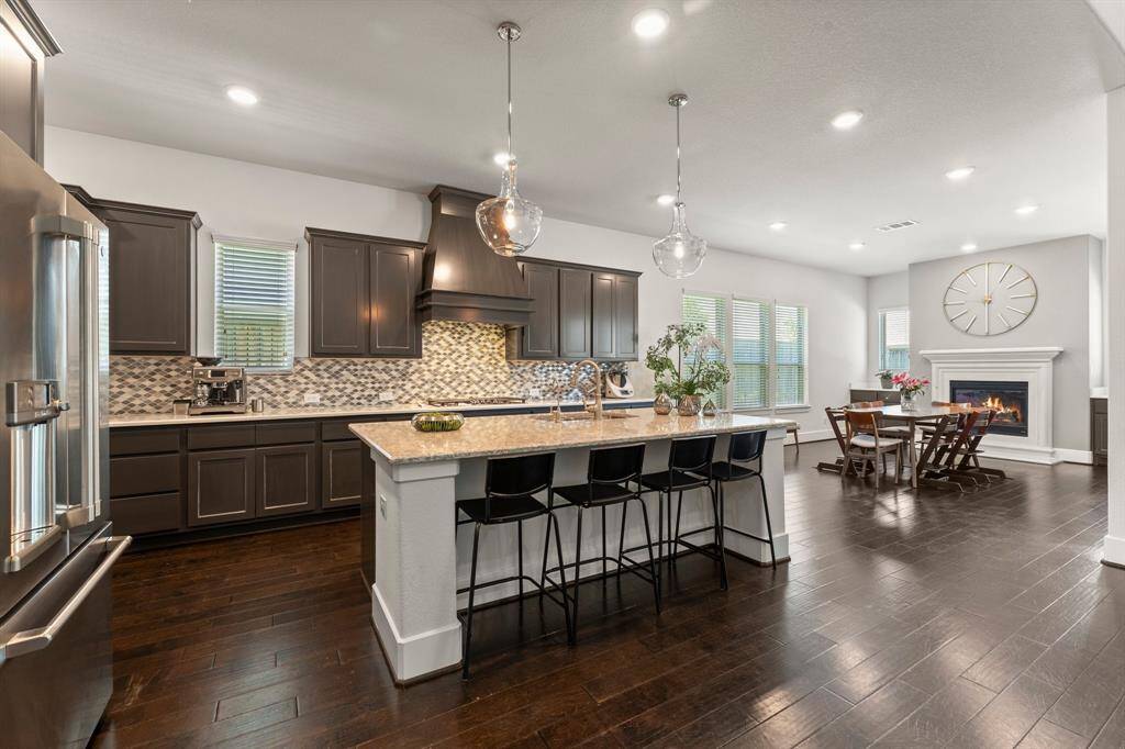 This wide-angle view captures the seamless connection between the gourmet kitchen and the fireplace-accented breakfast area—ideal for everyday comfort and effortless entertaining.