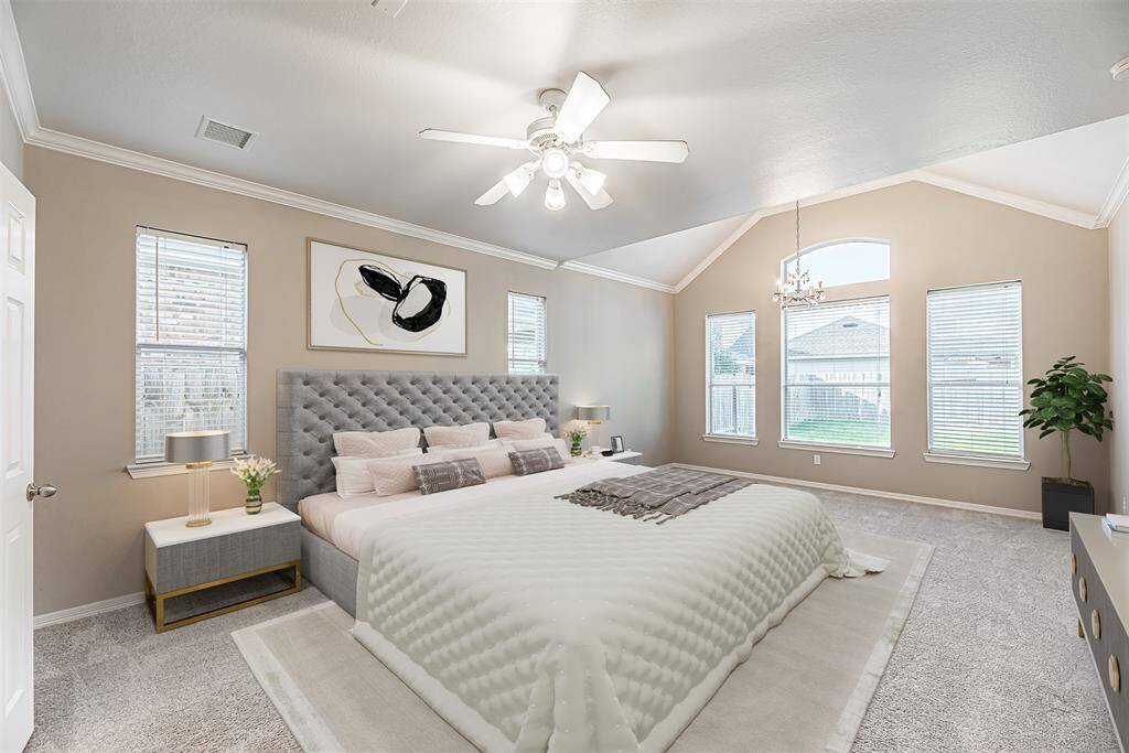 Primary bedroom is spacious with carpet, windows on two walls, crown molding and ceiling fan. *Virtually Staged*