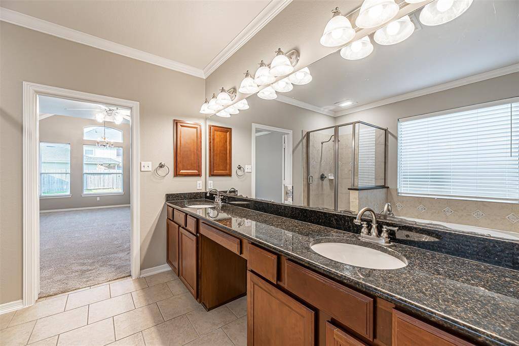 Primary bathroom has tile flooring, double under mount sinks and granite countertops.