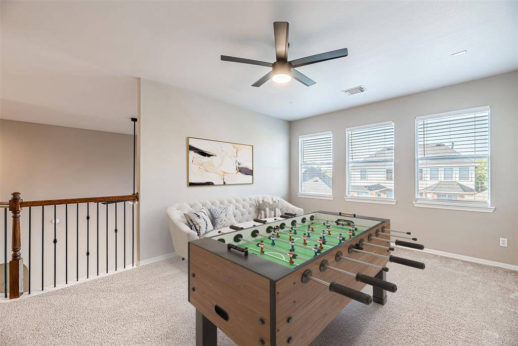 Game room upstairs has carpet, updated ceiling fan, and is open to the downstairs with decorative iron railing. *Virtually Staged*