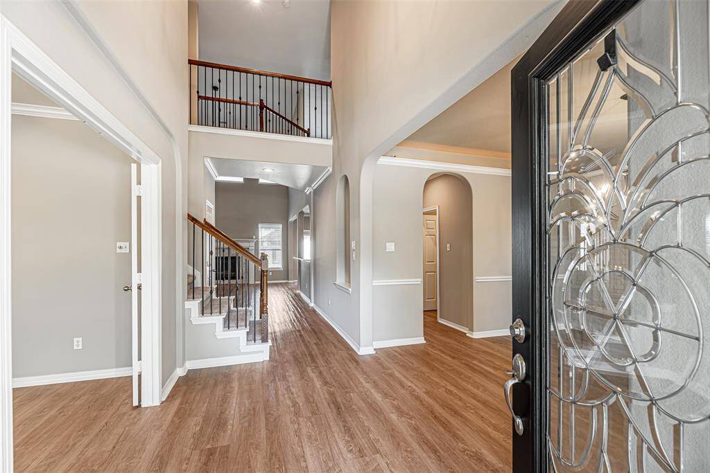 Grand two story front entry of home features decorative glass lead front door and lvp flooring.