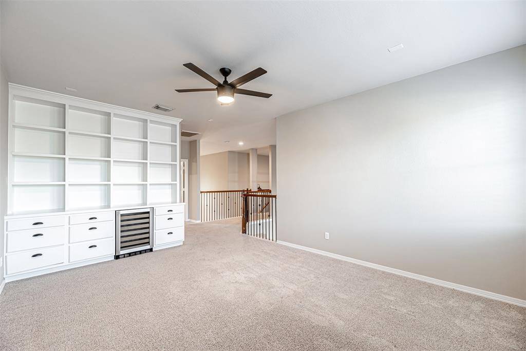 Game room has built in bookshelves with drawers and wine fridge.