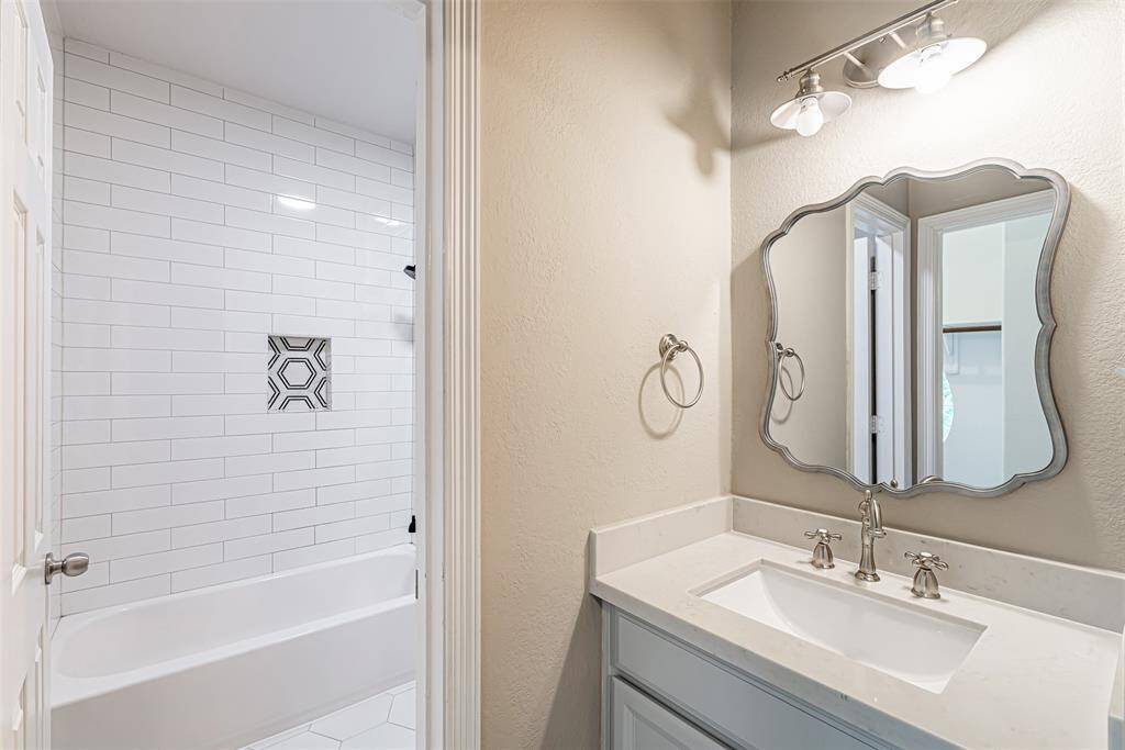 Updated hollywood bathroom has single sink vanity with quartz top and decorative mirror.