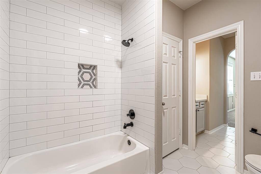 Updated tub/shower combo of hollywood bathroom with subway tile to ceiling and hexagon tile on the floors.
