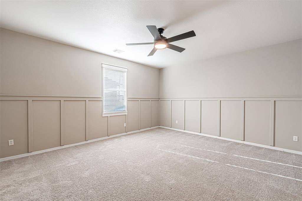 Additional bedroom upstairs has updated ceiling fan, carpet and decorative wainscotting.