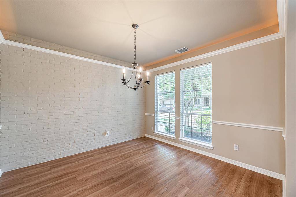 Dining room is just off the front entry and features crown molding, tray ceiling with lighting and decorative brick accent wall.