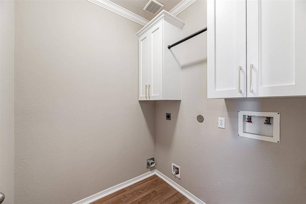 Utility room in house has lvp flooring, double cabinets for storage and handing rod.