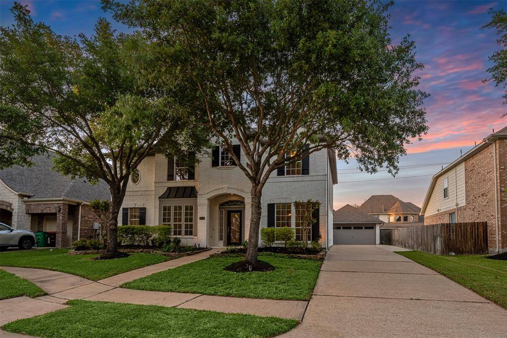 This home has a long driveway that extends out at the garage and mature trees.