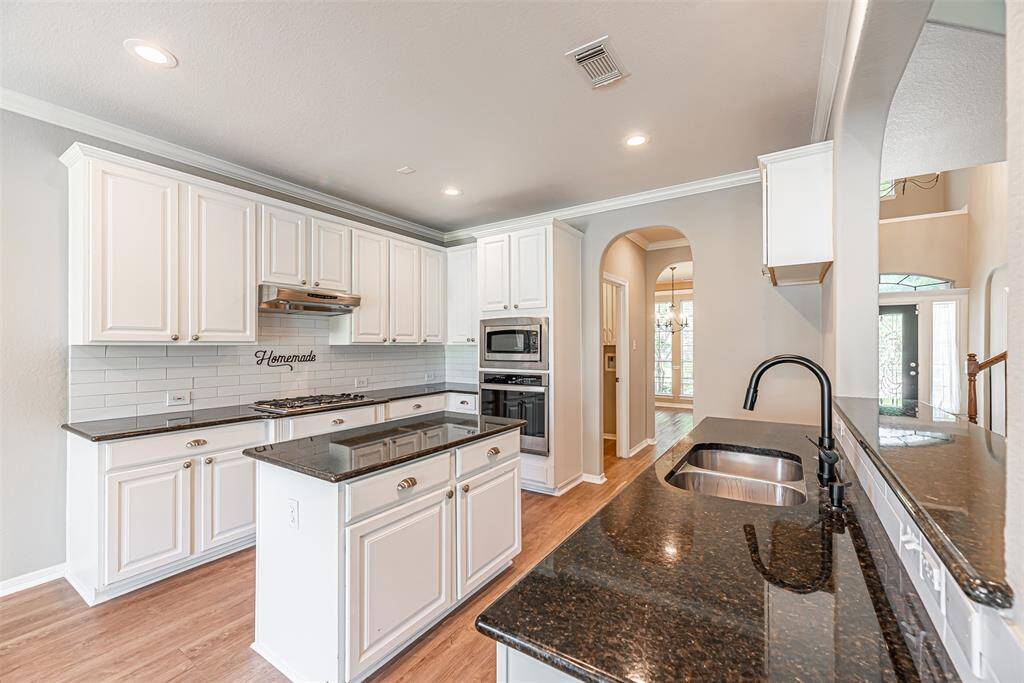 Kitchen is perfect for the chef in the family with granite counter tops, subway tile backsplash and island with plenty of prep space. There is also a gas range, oven that was replaced in 2023 and under mount kitchen sink.