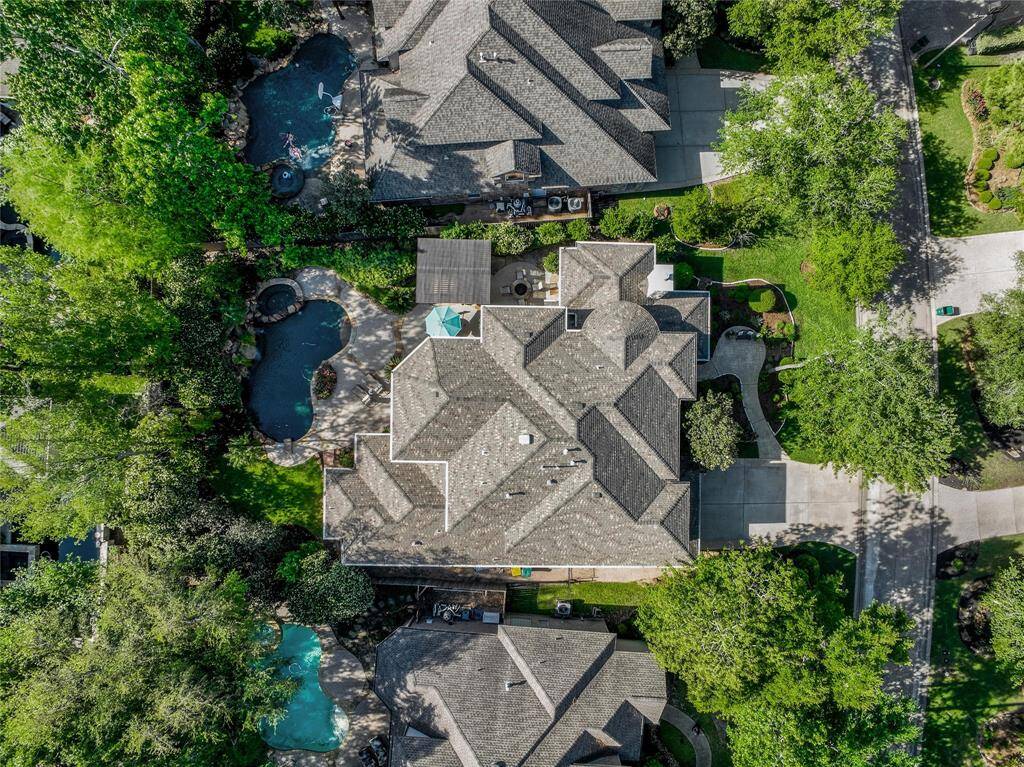 In this aerial view you can see the wonderful backyard and everything it has to offer, a large driveway and sitting area out front and what The Woodlands is known for - Trees!