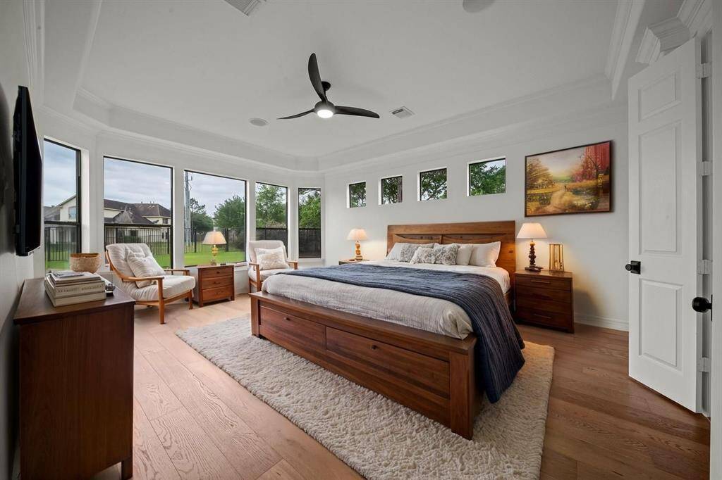 The primary bedroom provides a quiet retreat with floor to ceiling windows overlooking the backyard and waterview
