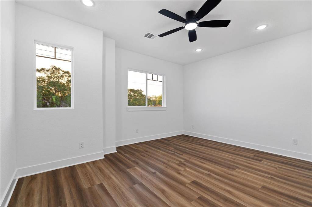 The second-story primary suite offers comfort and style with luxury vinyl flooring, recessed lighting, a ceiling fan, and a private en suite bathroom.