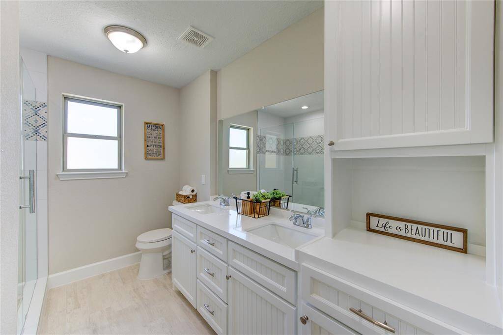 The primary bath includes a dual sink vanity space and custom built cabinetry.
