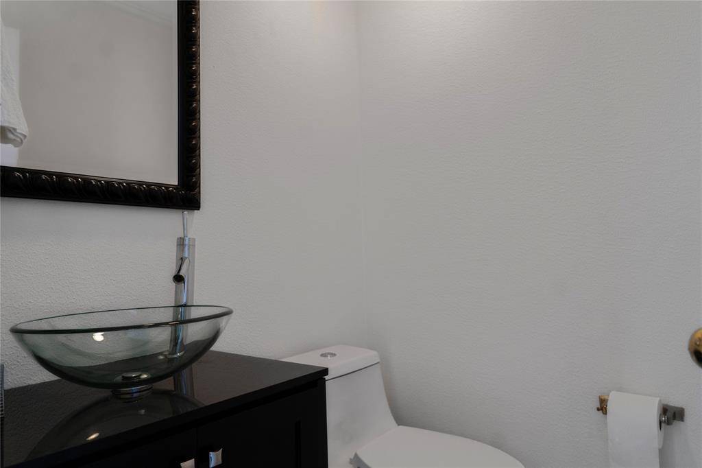The downstairs half bathroom showcases a modern design, featuring a stylish glass vessel sink and vanity.