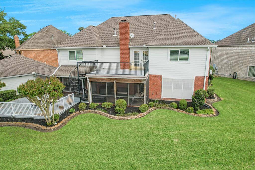 Look at the charming two-story home with a mix of brick and siding exterior. It features a spacious wooden deck with outdoor seating, ideal for relaxation or entertaining. The property is beautifully landscaped and offers serene views of a nearby pond, providing a peaceful and picturesque setting.