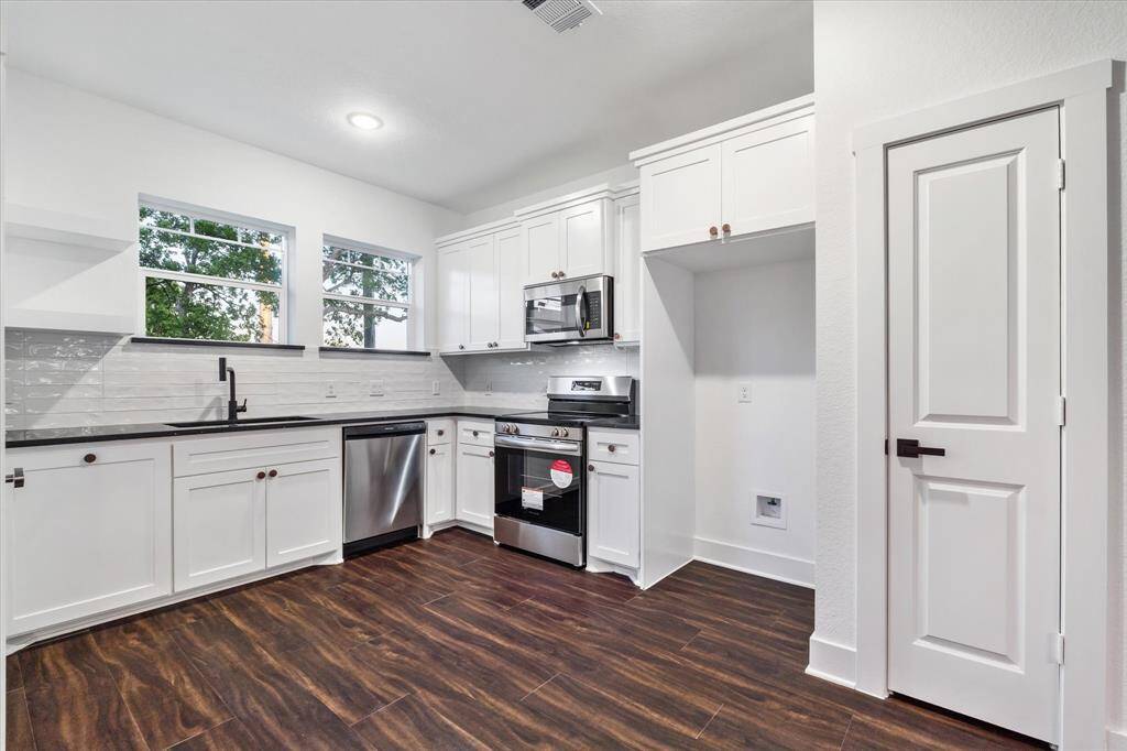You’ll love the kitchen—it’s got custom white cabinets, modern black fixtures, a fresh white subway backsplash, stainless steel appliances, recessed lights, and a pantry with tons of space. Also features black quartz countertops!