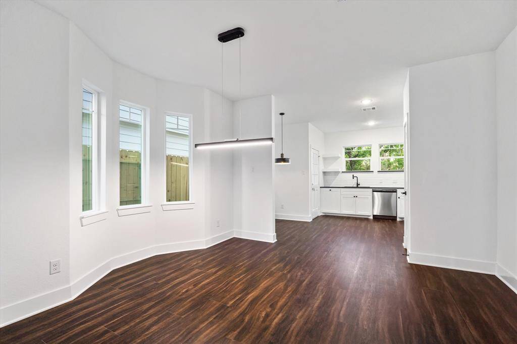 The dining space is full of character, with a classic black light fixture hanging above and graceful bay windows that let in plenty of daylight.