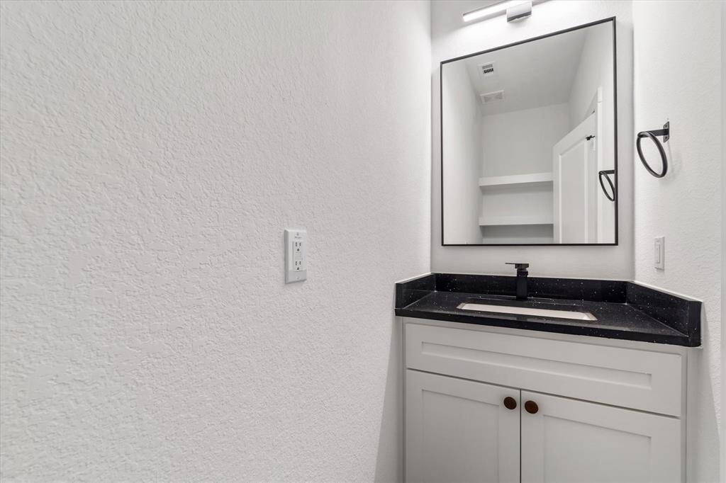 Next up is the half bath, complete with a bold black quartz counter and stylish black modern fixtures. You’ll also spot built-in shelves above the toilet—great for keeping towels or showing off your favorite decor.