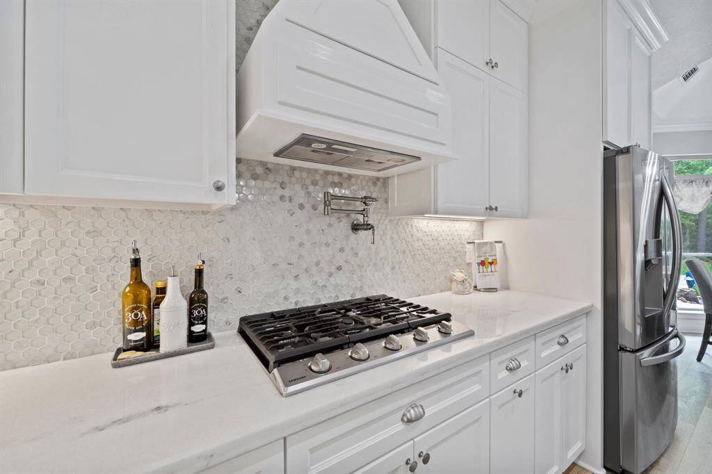 Gas cooktop, pot filler, custom range hood, under cabinet lighting- so many upgrades in this kitchen!