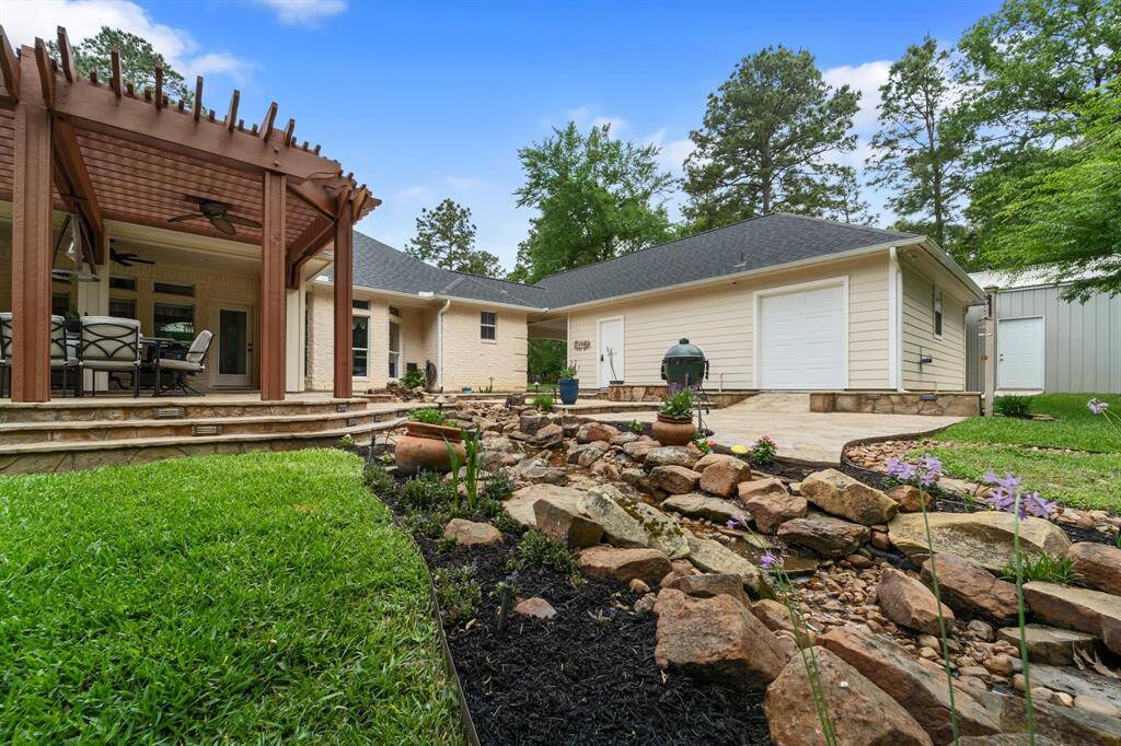 Professional landscaping in the back yard includes natural stone flowing water feature, sprinklers, LED lighting, and mature trees.