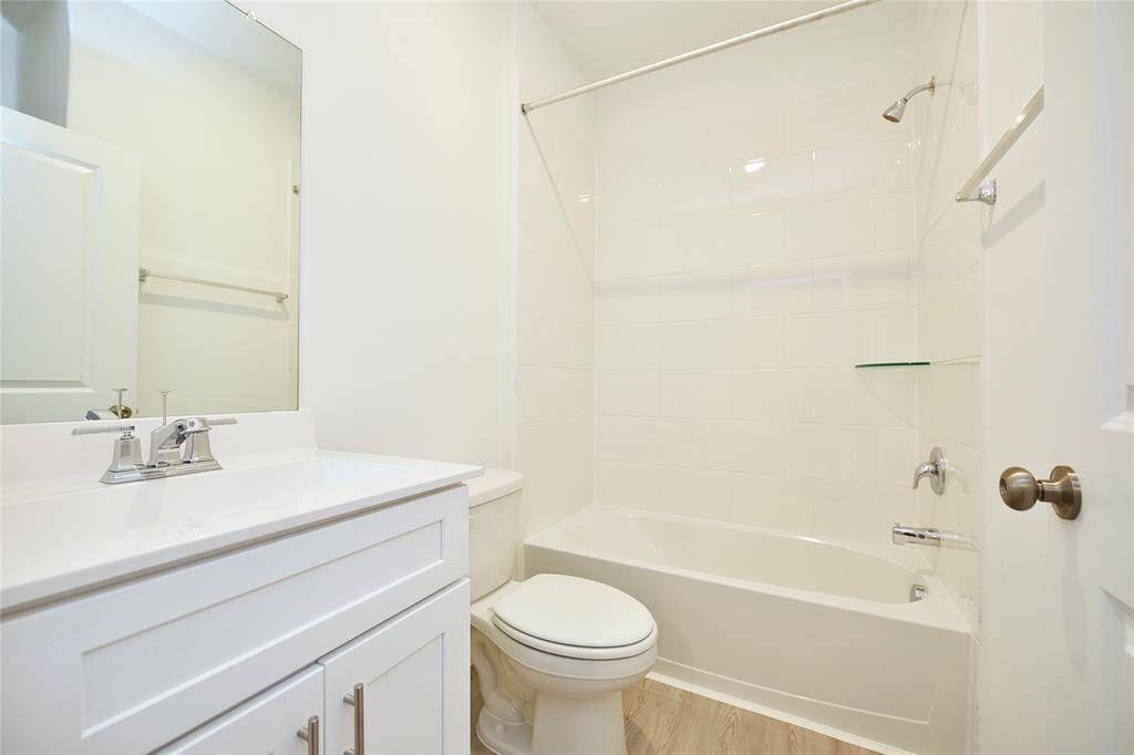 The secondary bathroom features a tub-shower combo, complemented by elegant marble countertops and stylish plank flooring for a modern look.