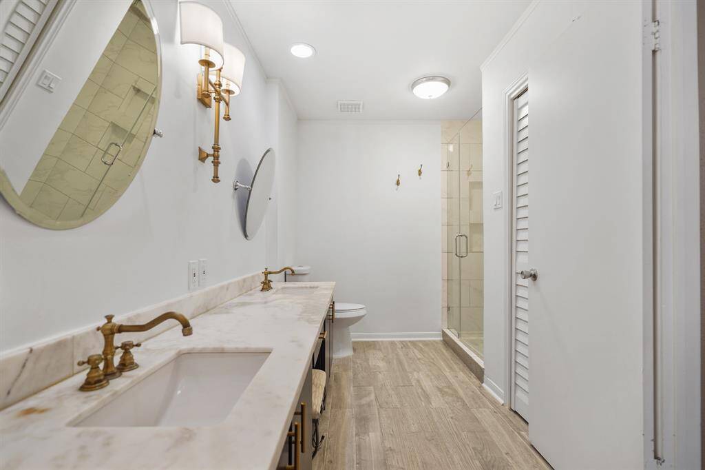 This remodeled primary bathroom now features a separate shower with built-in nooks, double sinks and a vanity space. The linen closet is huge and offers a ton of storage space.