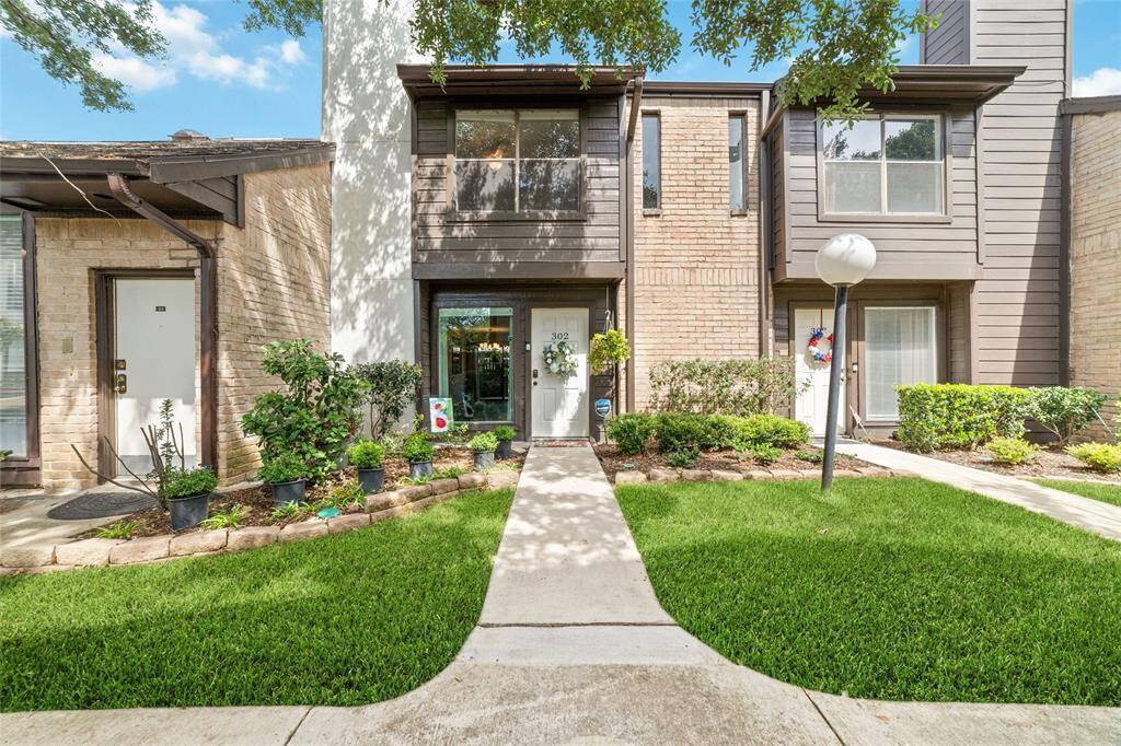 This charming townhouse features a cozy exterior with a classic blend of brick and siding details. Expansive windows fill the home with natural light, while the beautifully landscaped front yard and lush greenery create an inviting first impression.