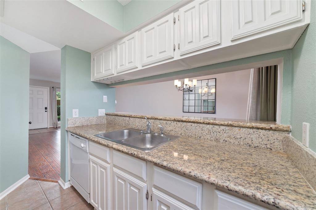 The kitchen has a welcoming flow, with a pass-through window through the bar top leading to the dining area, illuminated by a stylish chandelier. The open layout creates a seamless space, ideal for entertaining and casual meals.