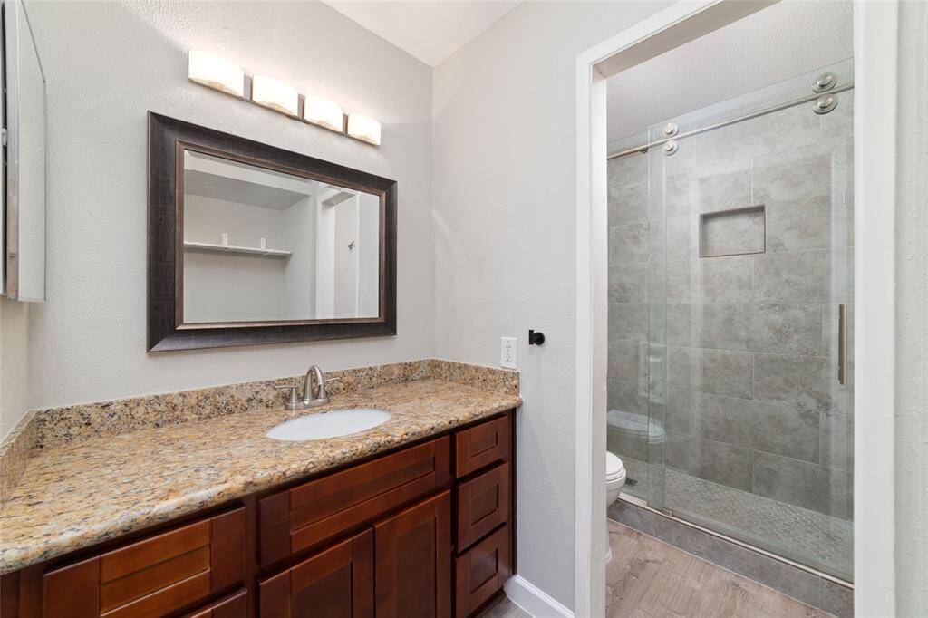 The walk-in shower takes center stage with sleek tilework and clear glass sliding doors, adding a spa-like touch to the space. Clean lines and a minimalist design make this bathroom very stylish!
