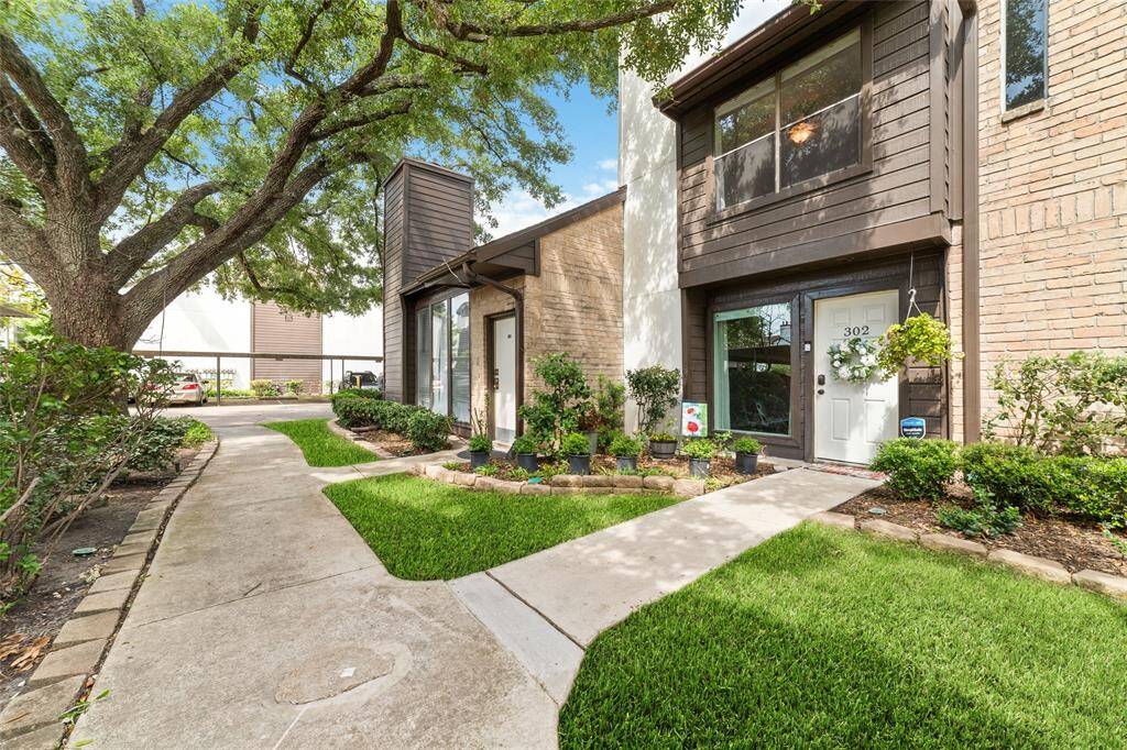 A picturesque townhouse community with timeless curb appeal, this exterior features a meticulously cared-for lawn, shady mature trees, and a lovely front path that guides you to the door. The entry feels warm and inviting, setting the tone for the rest of the home.