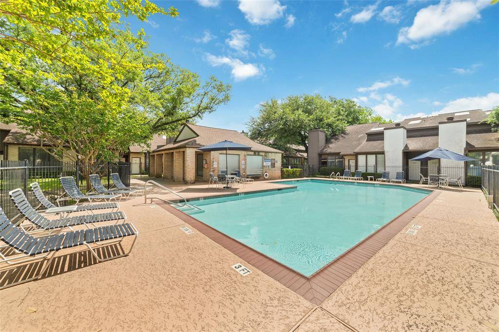 This photo captures an awesome community swimming pool, bordered by comfy lounge chairs and a clean, well-kept deck, perfect for unwinding or catching up with neighbors. Mature trees and nearby homes add to the peaceful, laid-back atmosphere!