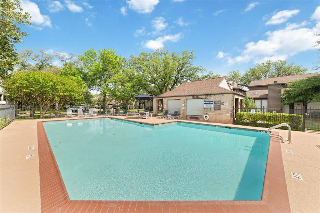 Another view of the peaceful community pool offers a quiet retreat, surrounded by lush trees that create a calm, natural setting, ideal for relaxing and enjoying the outdoors and sunshine!